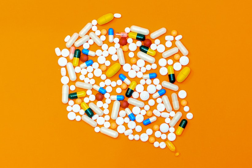 Colorful assorted pills on an orange background